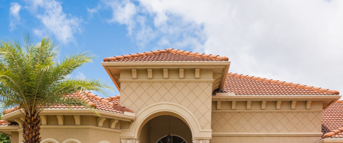 The front of a nice tan stone house with a brick roof.